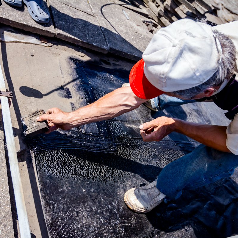 worker repairing an asphalt roofing system